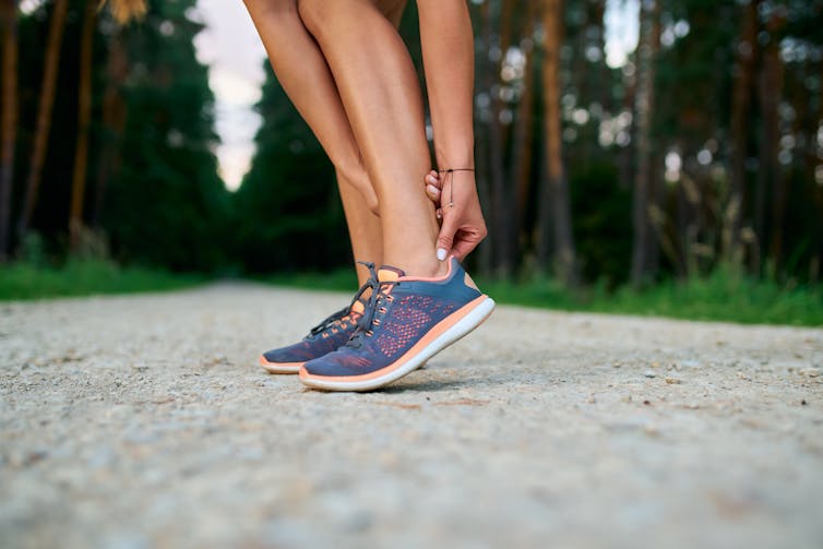 A person holds their achilles tendon in pain.